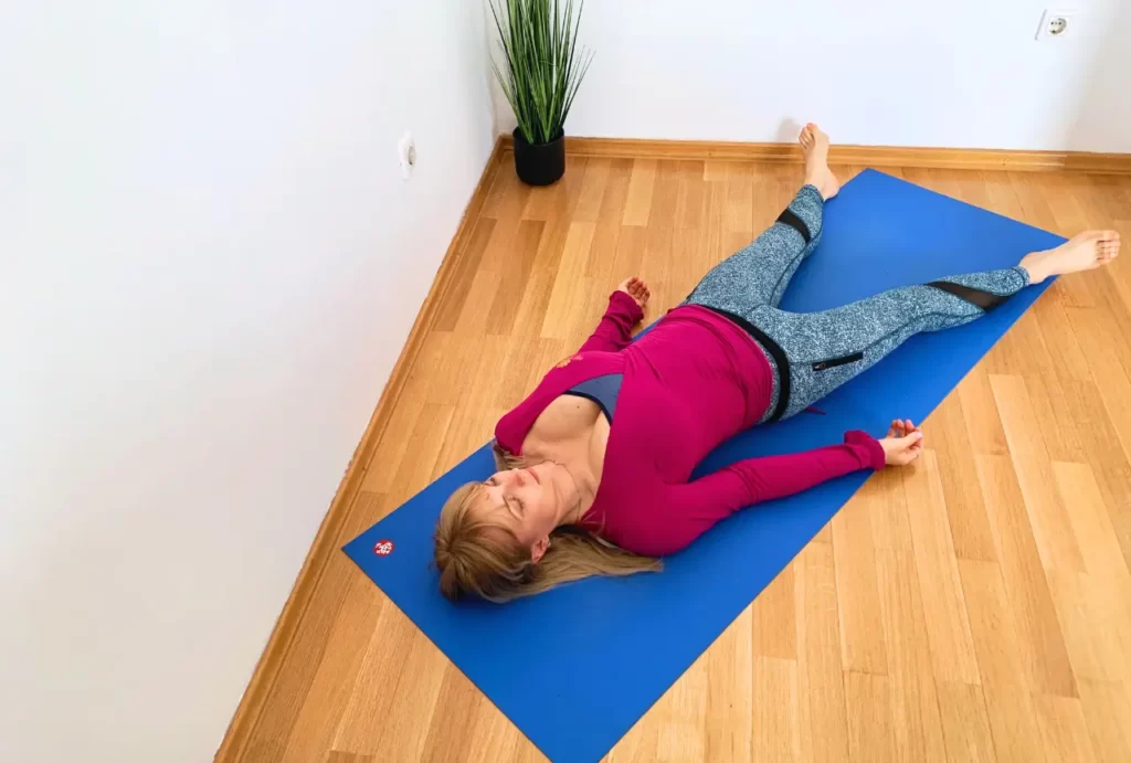 Romana radi yoga Nidru u Shavasani na plavoj prostirci