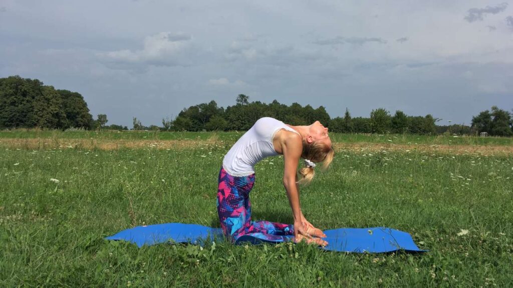 Romana izvodi Ustrasanu na plavoj prostirci u prirodi - otkriva životnu svrhu kroz praksu yoge