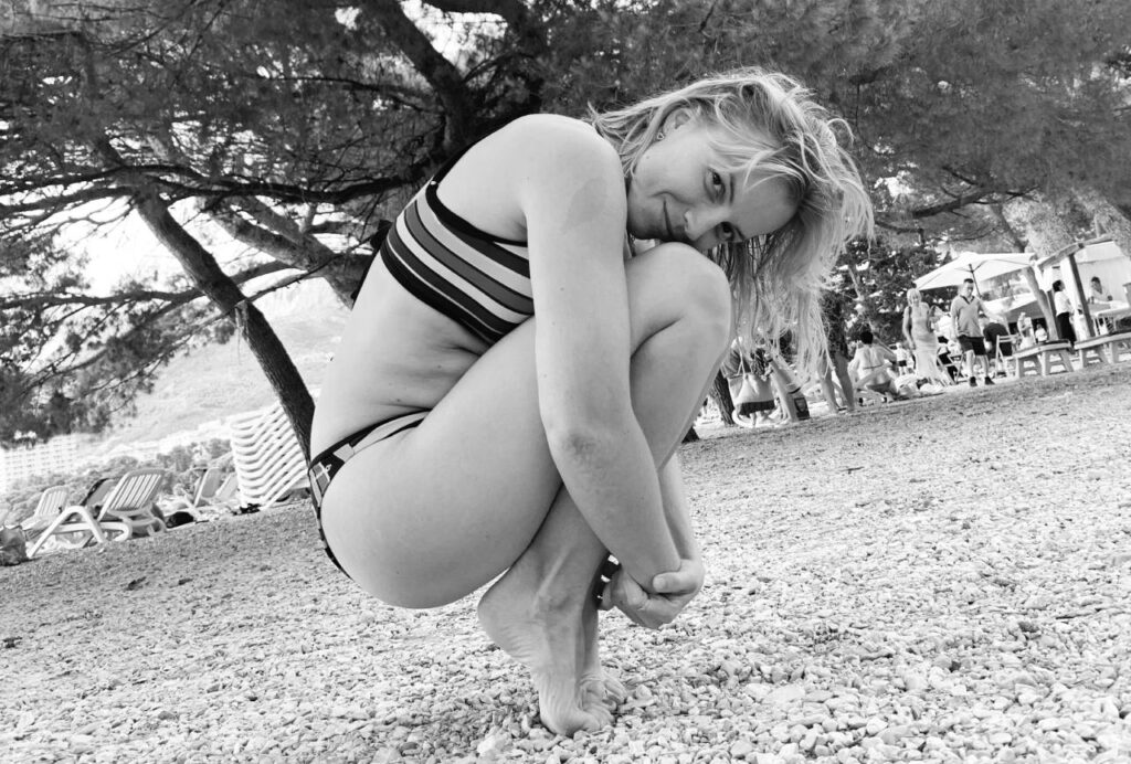 Zena cuci na vrhovima prstiju i rukama grli noge, crno bijela slika simbolizira pms i bolne mjesecnice